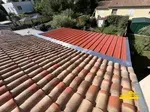 Extension de toiture en bac acier couleur rouge brique en cours de réalisation pour agrandir l'espace.
