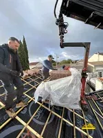 Grutage de matériaux pour monter les éléments sur la toiture d' une maison.