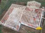 Vue aérienne d' une maison en construction avec la charpente visible.
