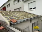 Pose de la première tuile sur le toit pour démarrer les travaux.
