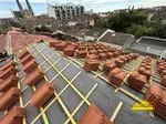 Chantier de pose de tuiles sur une maison en construction.