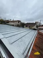 Vue d'une toiture en cours de construction avec les matériaux posés en zinc en joint debout.