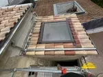 Intégration d'une bavette en plomb autour d'une fenêtre Velux sur le toit.